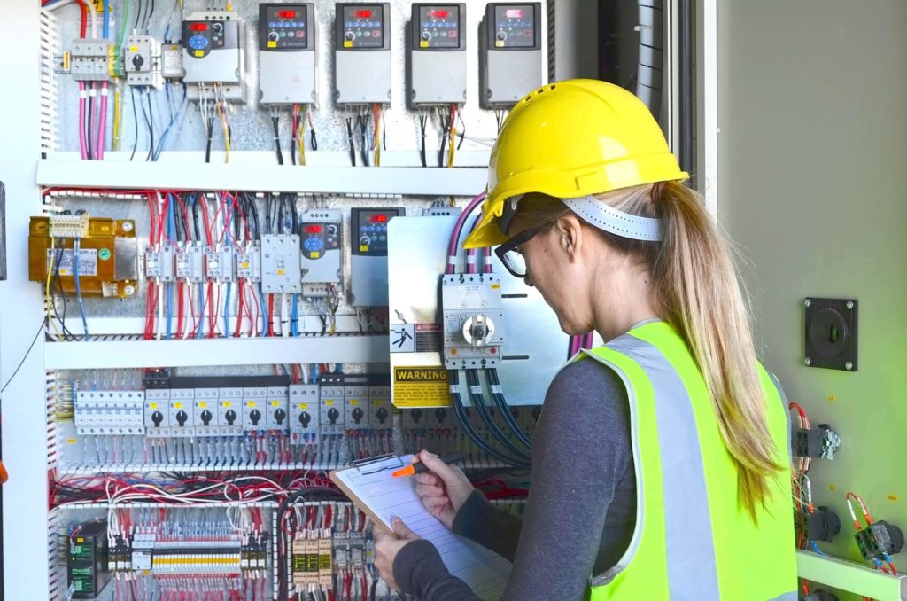 Person with hard hat in front of electric board