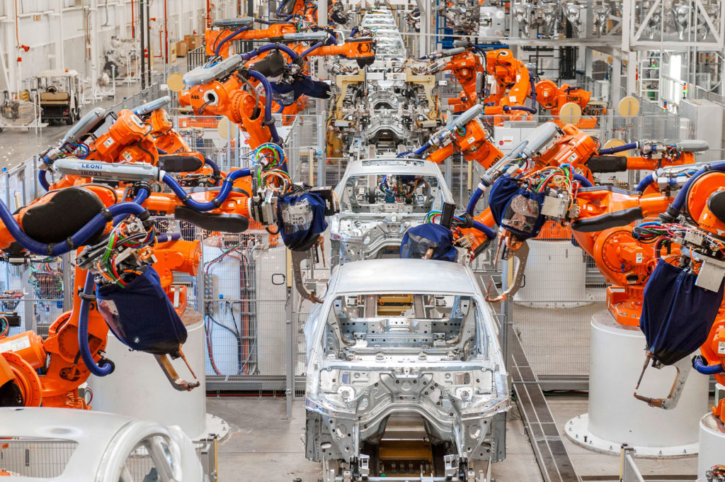 Flertal industrirobotar som i ett led sätter ihop bilar.