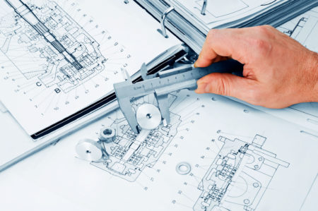 Hand över olika ritningar som använder ett mätinstrument för att mäta en mutter.