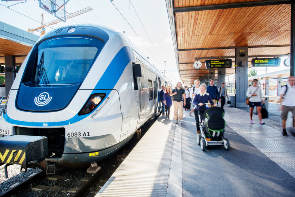 SL tåg vid perrongen en sommardag, personer lämnar tåget.